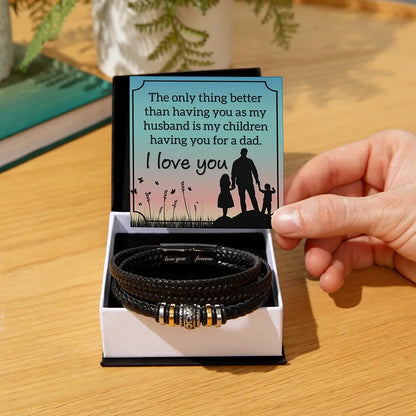 Black leather bracelet with gold accents in a box with a sentimental card on a wooden surface
