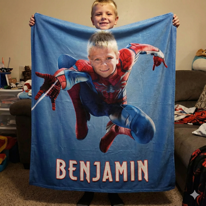 young boy holding spiderman blanket in his room